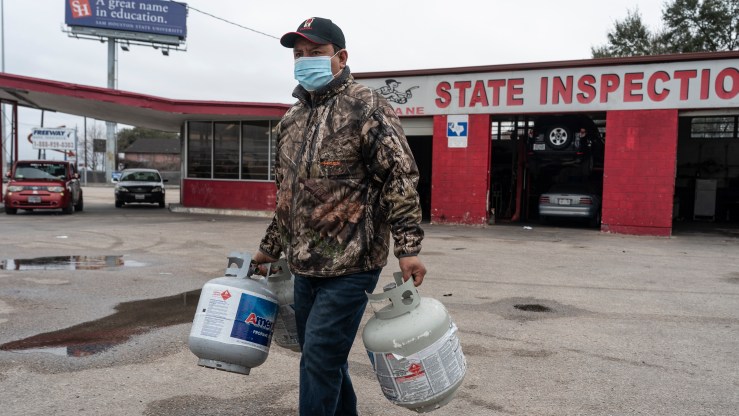 HOUSTON, TX - FEBRUARY 18: A person carries empty propane tanks, bringing them to refill at a propane gas station after winter weather caused electricity blackouts on February 18, 2021 in Houston, Texas. Winter storm Uri brought severe temperature drops causing a catastrophic failure of the power grid in Texas. About two million people are without electricity throughout Houston. (Photo by Go Nakamura/Getty Images)