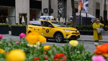 A woman and a yellow taxi cab stand near Rockefeller Center on April 2, 2021 in New York City.