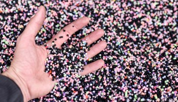 A hand sifts through plastic pellets used to make shoes in France. A new report by Beyond Plastics explains the ubiquitous material's environmental impact.