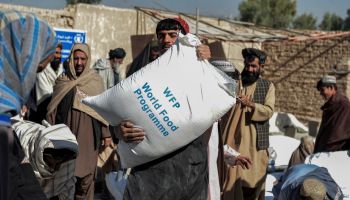 Afghan people carry sacks of food grains distributed as aid by the World Food Program in Kandahar, Afghanistan, on October 19, 2021.