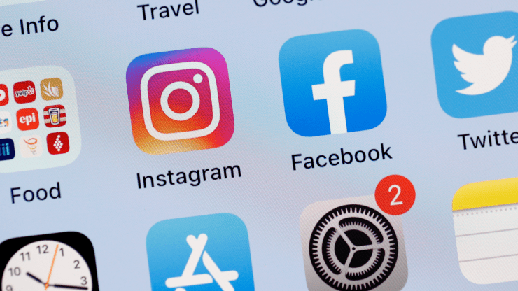 An iPhone screen shows the apps Instagram, Facebook, Twitter, and a folder of food apps on its home screen.