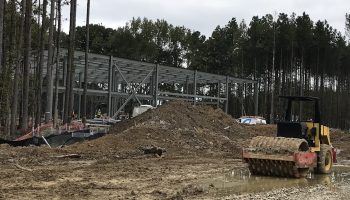 The stockpile construction site in Petersburg, Virginia. A pile of dirt and construction equipment sit in front of a building framework.