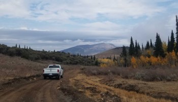 A U.S. Forest Service truck drives along a dirt road amid mountains, trees and cloudy skies in the Albion Mountains in southern Idaho.