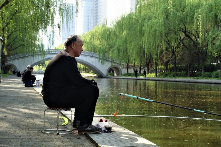 Retiree Li Cheng fishes along a canal in Luoyang city. He said this newer part of town used to be all farmland less than two decades ago. China's rapid development also contributes to its large carbon emissions. (Charles Zhang/Marketplace)