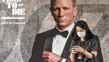 A woman walks past a poster for the new James Bond movie "No Time to Die" in Bangkok.