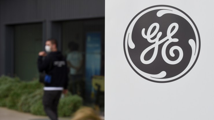 A worker walks at a General Electric plant in France with the GE logo visible.