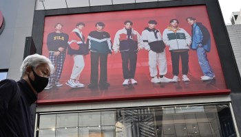 A man walks past a commercial poster showing K-pop group BTS members at a shopping district in Seoul on October 15, 2020. (Photo by Jung Yeon-je / AFP) (Photo by JUNG YEON-JE/AFP via Getty Images)