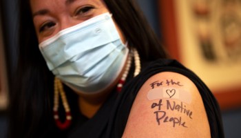 Abigail Echo-Hawk, chief research officer with Seattle Indian Health Board and a member of the Pawnee Tribe, shows off her arm after she received a shot of the Moderna COVID-19 vaccine in December 2020 in Seattle, Washington. A colleague used a black pen to inscribe, "For the ♡ of Native People" over the spot where she got the injection.