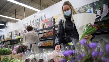 A customer wears a face mask while shopping for flowers at a wholesale merchant.