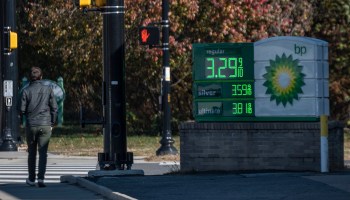 A man walks past a price board at a BP gas station in Arlington, Virginia, on Nov. 23. The price for regular gas reads $3.29.