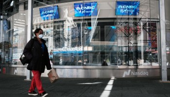 People walk by the Nasdaq Composite site in Times Square as global stocks fell on Tuesday as concerns mount that rising inflation will prompt central banks to tighten monetary policy on May 11, 2021 in New York City.
