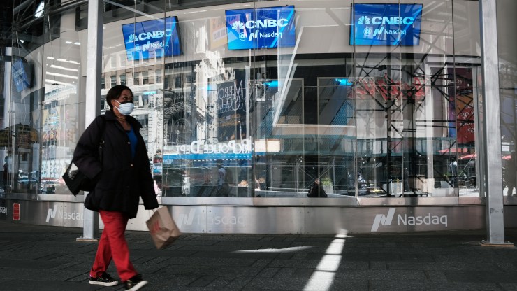 People walk by the Nasdaq Composite site in Times Square as global stocks fell on Tuesday as concerns mount that rising inflation will prompt central banks to tighten monetary policy on May 11, 2021 in New York City.