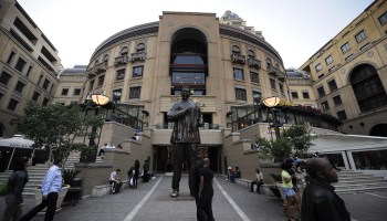 South Africans and tourists walk by the Nelson Mandela giant statue at Mandela Square on May 18, 2010 at Sandton City in Johannesburg, South Africa.