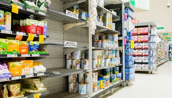 Shelves are almost empty of baby formula with signs warning customers that they are limited to 8 cans per customers