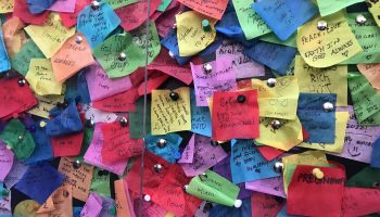Pieces of brightly colored confetti with handwritten wishes on them, pinned to a billboard in Times Square in December 2021.
