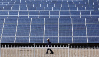 A Chinese worker walks near the solar modules of a newly installed 100MW photovoltaic on-grid power project in 2010 in Dunhuang of China's northwest Gansu Province.
