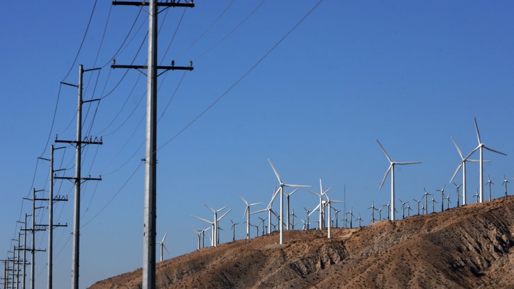 Windmills at a windfarm are seen in Palm Springs, California near a row of power lines.