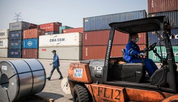 A forklift transports steel as a worker passes by at Yangluo container port on the Yangtze River on April 12, 2020, in Wuhan, Hubei Province, China.