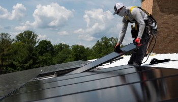 An employee with Ipsun Solar installs solar panels on the roof of the Peace Lutheran Church in Alexandria, Virginia, on May 17.