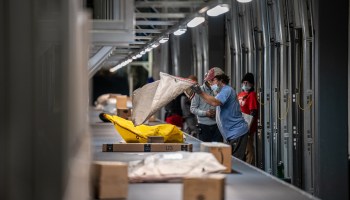 UPS package handlers move shipments from a conveyor belt into package cars at the UPS Centennial Ground Hub on December 6, 2021 in Louisville, Kentucky.