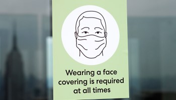 A sign reminding visitors to wear a face covering is displayed on a door at Top of the Rock Observation Deck as it reopens to the public during Phase 4 of re-opening following restrictions imposed to slow the spread of coronavirus on August 6, 2020 in New York City.