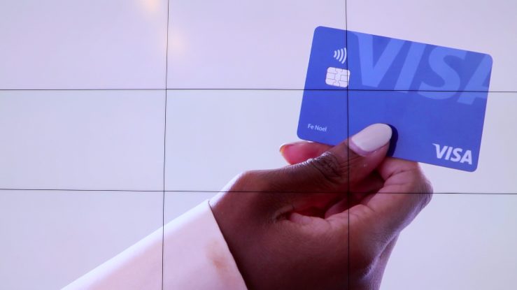 A hand holds a Visa card.
