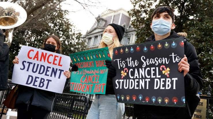 Activists hold festive signs calling on President Biden to cancel student debt and not resume student loan debt while musicians play joyful music, greeting the White House staff as they arrive to work on Dec. 15.