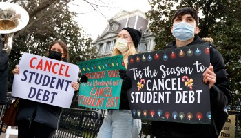 Activists hold festive signs calling on President Biden to cancel student debt and not resume student loan debt while musicians play joyful music, greeting the White House staff as they arrive to work on Dec. 15.
