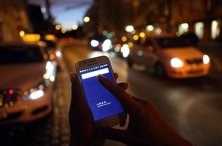 A woman uses the Uber app on a city street.