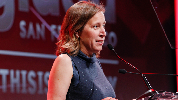Susan Wojcicki speaks at the GLAAD Gala wearing a navy dress as she speaks into a mic.