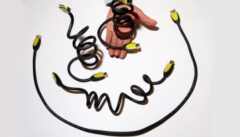 A hand holds out flexicord HDMI cables that are yellow and black on a white background.