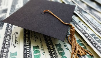 A tiny graduation cap sits atop $100 bills.