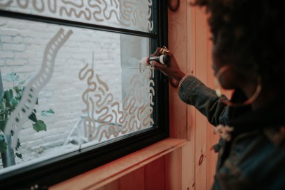 Artist Atiya Jones drawing on windows at Trace Brewing in Pittsburgh, Pennsylvania. (Photo by Julie Kahlbaugh)