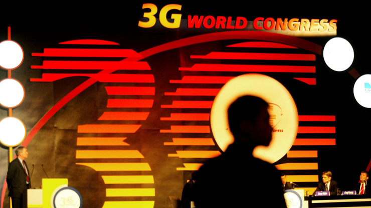A shadow stands in front of a red and yellow advertisement for the "3G World Congress."