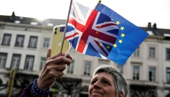 An anti-Brexit demonstrator holds British and European flags during a protest near the European Parliament in Brussels, on January 30, 2020. - Britain's departure from the European Union was set in law on January 29, amid emotional scenes, as the bloc's parliament voted to ratify the divorce papers. After half a century of sometimes awkward membership and three years of tense withdrawal talks, the UK will leave the EU at midnight Brussels time (2300 GMT) on January 31, 2020. (Photo by Kenzo TRIBOUILLARD / AFP) (Photo by KENZO TRIBOUILLARD/AFP via Getty Images)