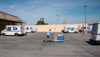A mail carrier pushes a cart out of a United States Postal Service sorting facility at the Remcon Circle United States Postal Service Post Office amid the coronavirus pandemic in on April 30, 2020 in El Paso, Texas.