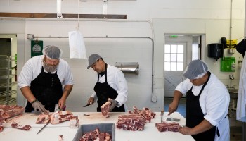 Three butchers cut meat.