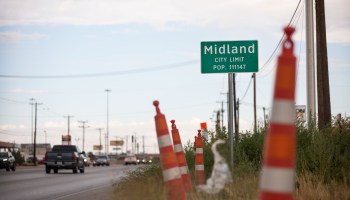 A city limit sign for Midland, Texas, in 2020, with cars driving in the background.