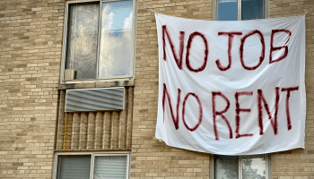 A white banner with the phrase, "No Job, No Rent" hangs on the exterior of a beige apartment building in Washington, D.C.