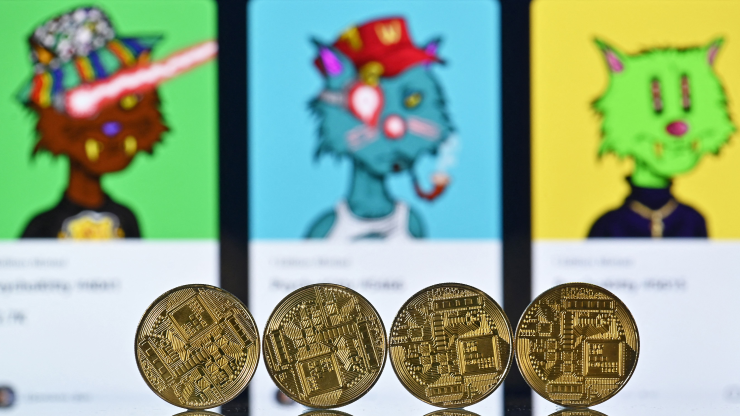On an NFT Marketplace, you can see three blurred out illustrations of cats and four golden crypto coins in the foreground.