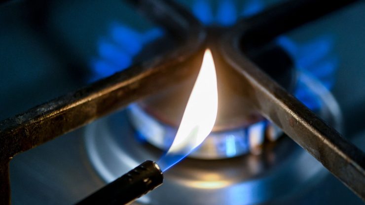 A flame is seen in front of a burner gas stove.
