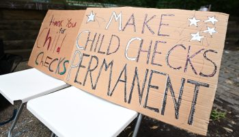 A cardboard sign that reads "make child checks permanent"