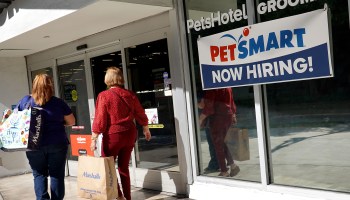 A Now Hiring sign hangs near the entrance to the PetSmart store on December 03, 2021 in Miami, Florida.