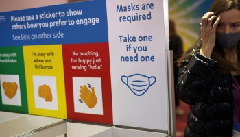 Free masks are provided as a sign that reminds attendees to keep their masks on is on display at the Las Vegas Convention Center on Day 1 of CES 2022, January 5, 2022 in Las Vegas, Nevada.