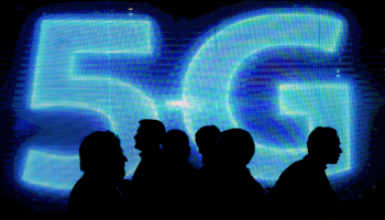 A group of silhouettes walk in front of a neon blue sign that reads "5G."