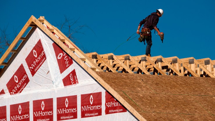 A construction worker builds a roof on a new home.