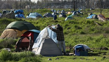 A homeless man adjusts a tent at a tent city in Sacramento, California, in 2009.