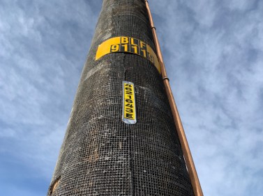 A newly refurbished utility pole wrapped in fire-resistant material stands at the entrance to the town of Acton, California. 