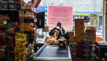 A person wearing a protective mask looks at a grocery receipt while shopping in a grocery store in the Bushwick neighborhood of Brooklyn.