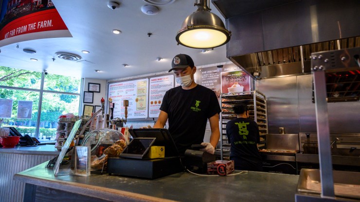 A young man wearing a face mask works at a fast food restaurant in Arlington, Virginia.